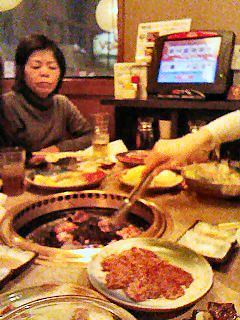 My mother-in-law watching us cook yakiniku. The electronic menu is in the background.